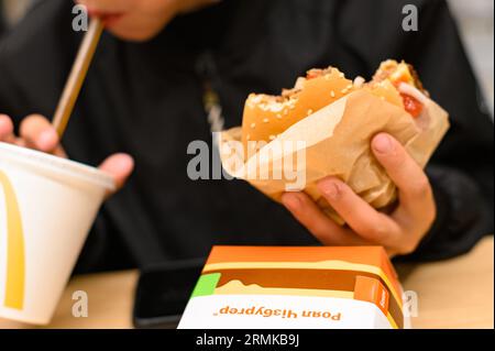 Ivano-Frankivsk, Ukraine, June 7, 2023: a little boy eats a royal cheeseburger at McDonald's. Stock Photo