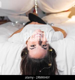 Gros plan femme couchée au lit avec ferry lumière sa caméra regardant les cheveux Banque D'Images