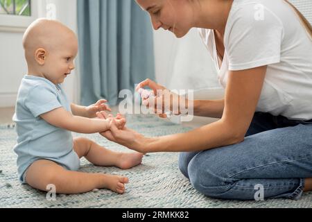 Vue latérale maman vaporisant le désinfectant pour les mains de l enfant Banque D'Images