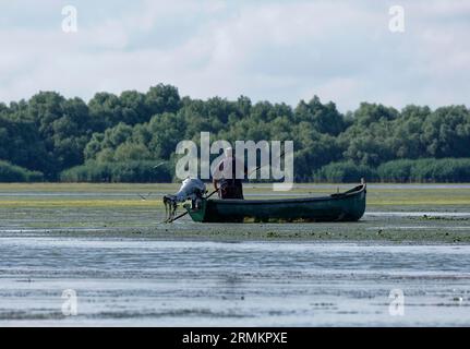 Pêcheurs dans un bateau sur l'eau de Lacul Isaccel, un lac dans le delta du Danube. Réserve de biosphère du delta du Danube UNESCO. Munghiol, Tulcea, Roumanie Banque D'Images