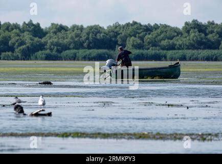 Pêcheurs dans un bateau sur l'eau de Lacul Isaccel, un lac dans le delta du Danube. Réserve de biosphère du delta du Danube UNESCO. Munghiol, Tulcea, Roumanie Banque D'Images