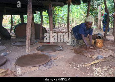 Femme fait un ustensile de cuisine en argile pour cuisiner Injera (crêpe comme du pain) sur un mogogo sur un feu Jinka, Omo Valley, Ethiopie Banque D'Images