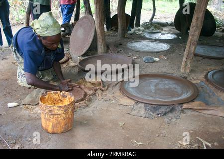 Femme fait un ustensile de cuisine en argile pour cuisiner Injera (crêpe comme du pain) sur un mogogo sur un feu Jinka, Omo Valley, Ethiopie Banque D'Images