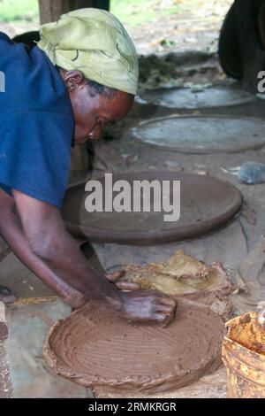 Femme fait un ustensile de cuisine en argile pour cuisiner Injera (crêpe comme du pain) sur un mogogo sur un feu Jinka, Omo Valley, Ethiopie Banque D'Images