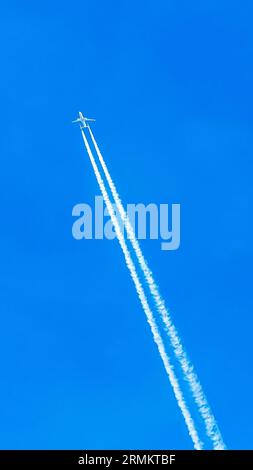 Avion bimoteur en vol avec traînées de condensation Banque D'Images