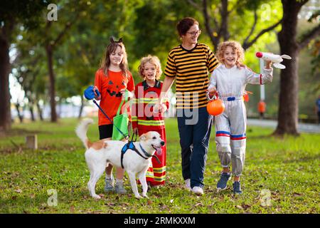 Les enfants se déguent en costume d'Halloween. Les enfants de couleur s'habillent avec un seau à bonbons dans la rue de banlieue. Petit garçon et fille trick ou traitement Banque D'Images