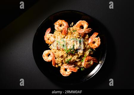 Risotto aux moules et crevettes sur une assiette noire Banque D'Images