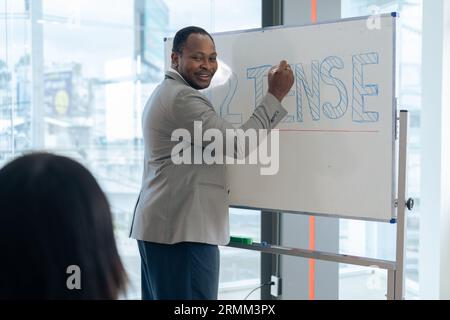 Le professeur de calcul masculin senior africain écrit sur tableau blanc dans la salle de classe Banque D'Images