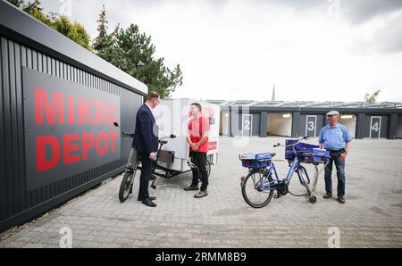 29 août 2023, Schleswig-Holstein, Lübeck : Jan Lindenau (SPD, l), maire de Lübeck, Matthias Jendrian (M), entreprise de logistique vélo Lü-Bike, et Erhard Schmidt, livreur chez Nordbrief, parlent à l'ouverture du premier microdépôt à Lübeck. Le dépôt est destiné à soulager la vieille ville de Lübeck du trafic de courrier et de livraison. Photo : Christian Charisius/dpa Banque D'Images