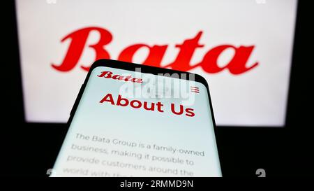 Téléphone portable avec le site Web de la société de chaussures Bata Corporation sur l'écran devant le logo de l'entreprise. Effectuez le focus sur le coin supérieur gauche de l'écran du téléphone. Banque D'Images