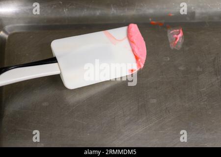 chef pâtissier styr crème au beurre rouge pour la décoration des gâteaux dans la cuisine professionnelle Banque D'Images