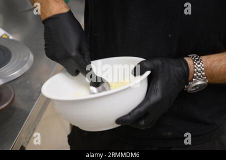 chef pâtissier styr crème au beurre rouge pour la décoration des gâteaux dans la cuisine professionnelle Banque D'Images