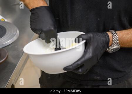 chef pâtissier styr crème au beurre rouge pour la décoration des gâteaux dans la cuisine professionnelle Banque D'Images