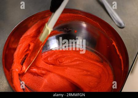 chef pâtissier styr crème au beurre rouge pour la décoration des gâteaux dans la cuisine professionnelle Banque D'Images