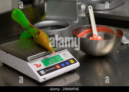 chef pâtissier styr crème au beurre rouge pour la décoration des gâteaux dans la cuisine professionnelle Banque D'Images