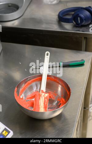 chef pâtissier styr crème au beurre rouge pour la décoration des gâteaux dans la cuisine professionnelle Banque D'Images