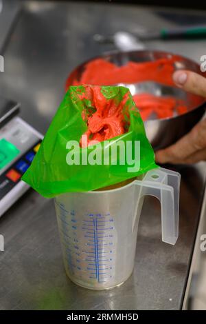 chef pâtissier styr crème au beurre rouge pour la décoration des gâteaux dans la cuisine professionnelle Banque D'Images