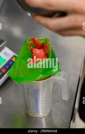 chef pâtissier styr crème au beurre rouge pour la décoration des gâteaux dans la cuisine professionnelle Banque D'Images