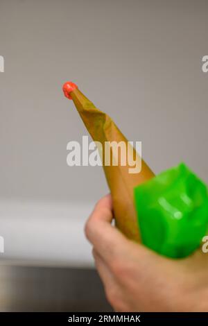 chef pâtissier styr crème au beurre rouge pour la décoration des gâteaux dans la cuisine professionnelle Banque D'Images