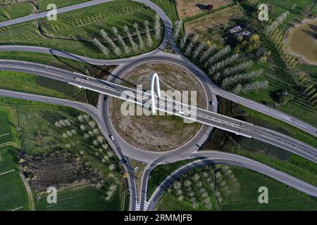 Vue zénithale aérienne d'un rond-point avec une arche du pont suspendu par Santiago Calatrava à Reggio Emilia. Reggio Emilia, Italie Banque D'Images