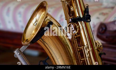 Détail d'un saxophone ténor sur un support devant un canapé. Banque D'Images