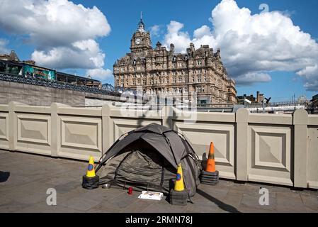 Tente de personnes sans abri plantée sur le pont Waverley avec l'hôtel cinq étoiles Balmoral en arrière-plan. Édimbourg, Écosse, Royaume-Uni. Banque D'Images