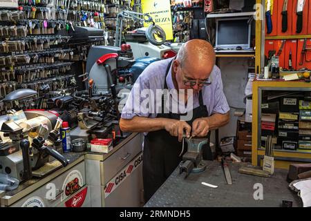 Un broyeur à couteaux âgé et expert dans son atelier broie une paire de ciseaux sur la meule de pierre. Ascoli Piceno, région des Marches, Italie, Europe Banque D'Images