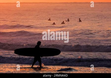 Île de Palms, États-Unis. 29 août 2023. Un surfeur démodé par le spectaculaire lever du soleil vérifie les conditions de vagues causées par le passage de l'ouragan Franklin avant de rejoindre ses collègues surfeurs, le 29 août 2023 à Isle of Palms, Caroline du Sud. L’ouragan Franklin, une tempête monstre de catégorie 4, se dirige vers les Bermudes tandis que l’ouragan Idalia devrait passer au-dessus de ses têtes jeudi. Crédit : Richard Ellis/Richard Ellis/Alamy Live News Banque D'Images