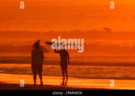 Île de Palms, États-Unis. 29 août 2023. Les surfeurs silhouettés par le lever du soleil vérifient les conditions de vagues causées par le passage de l'ouragan Franklin avant de partir dans l'eau, le 29 août 2023 à Isle of Palms, Caroline du Sud. L’ouragan Franklin, une tempête monstre de catégorie 4, se dirige vers les Bermudes tandis que l’ouragan Idalia devrait passer au-dessus de ses têtes jeudi. Crédit : Richard Ellis/Richard Ellis/Alamy Live News Banque D'Images