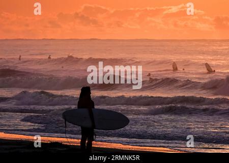 Île de Palms, États-Unis. 29 août 2023. Un surfeur, silhouetté par le spectaculaire lever du soleil, vérifie les conditions de vagues causées par le passage de l'ouragan Franklin avant de partir dans l'eau, le 29 août 2023 à Isle of Palms, Caroline du Sud. L’ouragan Franklin, une tempête monstre de catégorie 4, se dirige vers les Bermudes tandis que l’ouragan Idalia devrait passer au-dessus de ses têtes jeudi. Crédit : Richard Ellis/Richard Ellis/Alamy Live News Banque D'Images