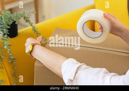 Femme tapant la boîte en carton dans le bureau le jour du déménagement, closeup Banque D'Images