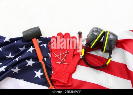 Équipement de protection, outils et drapeau américain sur fond blanc. Célébration de la fête du travail Banque D'Images