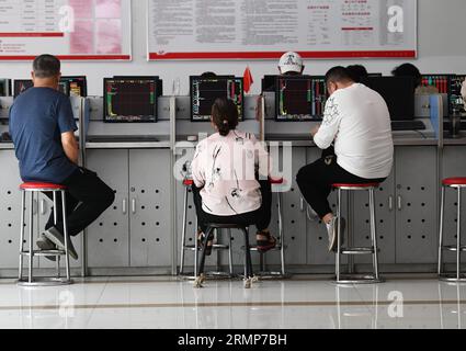 Plusieurs investisseurs sont attentifs aux changements dans l'indice composite de Shanghai affiché sur les écrans d'ordinateur du Fuyang Hua'an Securities Trading Office. Le ministère des Finances et l’Administration fiscale d’État ont annoncé dans un communiqué du 27 août que la Chine réduirait de moitié le droit de timbre sur les transactions boursières à partir du 28 août afin de revitaliser les marchés financiers et de renforcer la confiance des investisseurs. Banque D'Images