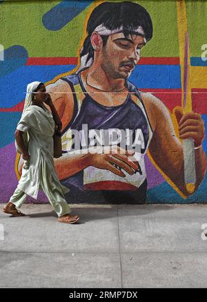 Mumbai, Maharashtra, Inde. 29 août 2023. Une femme qui parle sur son téléphone portable passe devant une peinture murale représentant l'athlète indien Neeraj Chopra à Mumbai. Neeraj Chopra est devenu le premier Indien à remporter la médaille d'or au Championnat du monde d'athlétisme organisé à Budapest en Hongrie. Il a réussi à lancer le javelot à une distance de 88.17m qui lui a valu la médaille d'or devant le pakistanais Arshad Nadeem qui a remporté une médaille d'argent. (Image de crédit : © Ashish Vaishnav/SOPA Images via ZUMA Press Wire) USAGE ÉDITORIAL SEULEMENT! Non destiné à UN USAGE commercial ! Banque D'Images