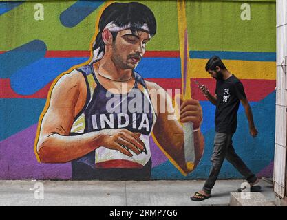 Mumbai, Maharashtra, Inde. 29 août 2023. Un homme regardant son téléphone portable passe devant une peinture murale représentant l'athlète indien Neeraj Chopra à Mumbai. Neeraj Chopra est devenu le premier Indien à remporter la médaille d'or au Championnat du monde d'athlétisme organisé à Budapest en Hongrie. Il a réussi à lancer le javelot à une distance de 88.17m qui lui a valu la médaille d'or devant le pakistanais Arshad Nadeem qui a remporté une médaille d'argent. (Image de crédit : © Ashish Vaishnav/SOPA Images via ZUMA Press Wire) USAGE ÉDITORIAL SEULEMENT! Non destiné à UN USAGE commercial ! Banque D'Images