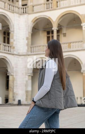 Une femme voyageur dans des lieux historiques regarde autour de la cour d'un monument dans le château de Krakow Wawel. Tourisme dans un lieu historique le jour ensoleillé. Femme Tourisme et blogging partage en direct en ligne pour le voyage de l'auditoire ensemble Banque D'Images