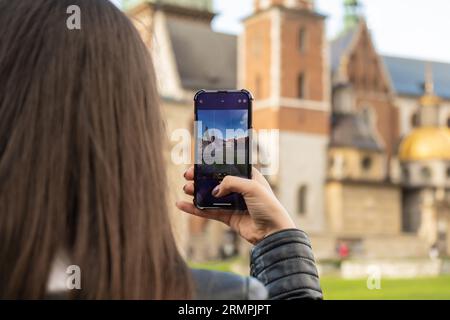 Une femme voyageur dans des lieux historiques regarde autour de la cour d'un monument et tourne de courtes vidéos au téléphone. Photos touristiques lieu historique le jour ensoleillé. Femme méconnaissable Tourisme et blogging partage en ligne pour le public Voyage ensemble enregistrement vidéo sur téléphone mobile Banque D'Images