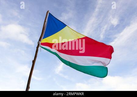 Le drapeau des Seychelles agitant dans le vent sous un ciel bleu nuageux par une journée ensoleillée, photo en gros plan Banque D'Images