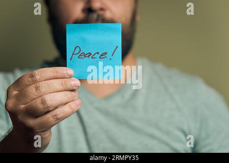 Un européen barbu tient un autocollant bleu devant lui, avec le mot paix Banque D'Images