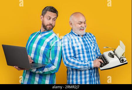 les hommes positifs montrent contre la nostalgie en arrière-plan. photo des hommes montrer contre la nostalgie avec ordinateur portable et machine à écrire rétro. les hommes montrent contre nostalgie isola Banque D'Images