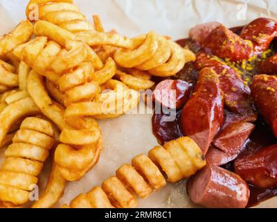 Currywurst allemand traditionnel, servi avec des frites sur Une assiette blanche.Table en bois comme arrière-plan. Banque D'Images