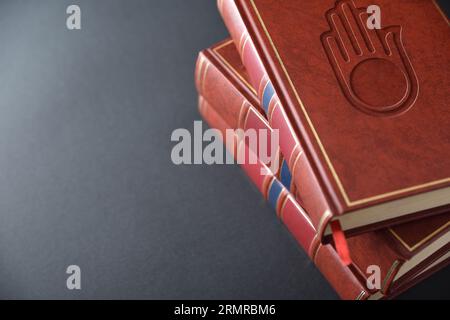 Pile de livres avec couverture en cuir brun avec symbole gravé de la culture et de la religion jaïnes sur la table noire. Vue surélevée. Banque D'Images