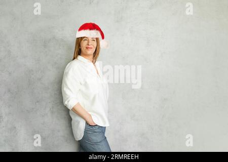 Heureuse femme mature dans le chapeau rouge de Santa intérieur Banque D'Images