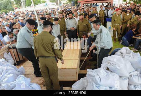 Les soldats israéliens déposent le cercueil du major Amotz Greenberg, un soldat de réserve de 45 ans tué en combattant un groupe de militants palestiniens qui ont infiltré Israël par un tunnel depuis le centre de la bande de Gaza, lors de ses funérailles à Hod Hasharon, près de tel Aviv, en Israël, le 20 juillet 2014. Treize soldats israéliens ont été tués pendant la nuit et au début de dimanche dans des affrontements avec des militants palestiniens dans toute la bande de Gaza, au milieu de l incursion terrestre de l armée israélienne dans l enclave, ont confirmé les Forces de défense israéliennes (FDI) dans un communiqué. (XINHUA/JINI) ISRAËL-GAZA-OPÉRATION TERRESTRE-13 SOLDATS ISRAÉLIENS-KIL Banque D'Images