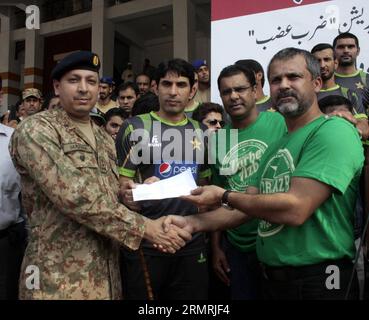 Moin Khan (à droite), le responsable de l'équipe pakistanaise de cricket, et le capitaine Misbah-ul-Haq (à droite) posent pour une photo alors qu'ils remettent un chèque à un responsable de l'armée pakistanaise pour faire des dons en faveur de civils déplacés par une opération militaire contre des militants au Nord-Waziristan, alors qu ils sont envoyés à Bannu, dans l est du Pakistan à Lahore le 22 juillet 2014. (Xinhua/Jamil Ahmed) PAKISTAN-LAHORE-FOURNITURES DE SECOURS PUBLICATIONxNOTxINxCHN responsable de l'équipe pakistanaise de cricket et chef Moin Khan r et capitaine de l'équipe UL Haq C posent pour une photo alors qu'ils remettent un chèque à un officiel de l'armée pakistanaise pour aller vers d. Banque D'Images