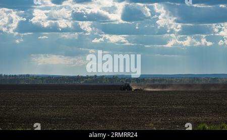 Un champ labouré de terre noire, avec un tracteur en état de marche, en Ukraine Banque D'Images