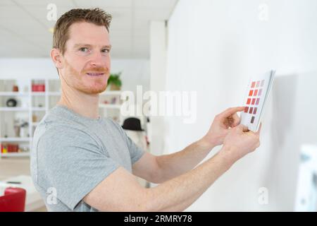 homme tenant des échantillons de couleur de peinture jusqu'au mur Banque D'Images