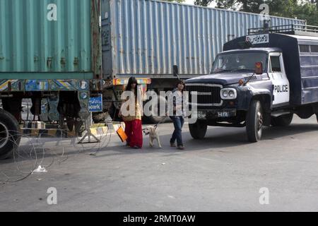 LAHORE, le 7 août 2014 -- des femmes pakistanaises traversent la route alors que des conteneurs sont placés pour bloquer la zone près de la maison de l'érudit religieux Tahir-ul-Qadri avant le prochain rassemblement anti-gouvernemental du Pakistan Awami Tehreek (PAT) dans l'est du Pakistan Lahore le 7 août 2014. Tahir-ul-Qadri, a lancé une campagne contre Nawaz Sharif et a laissé entendre qu il se joindrait à la longue marche de Khan. La menace d'une manifestation nationale du Tehrik-e-Insaf dirigé par Imran Khan, un politicien devenu joueur de cricket, a fait pression sur le gouvernement du Premier ministre pakistanais Nawaz Sharif. PAKISTAN-LAHORE-PROTESTATION ANTI-GOUVERNEMENTALE JAMILXAHME Banque D'Images