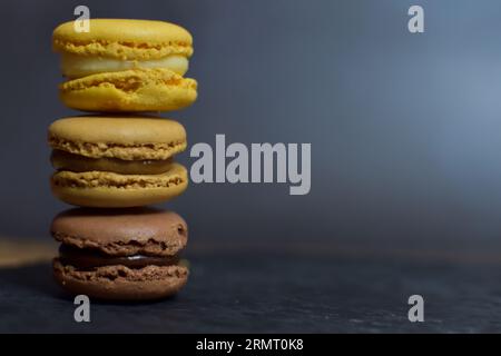 Macarons brown and yellow tones, on a slate plate with a black background. Stock Photo