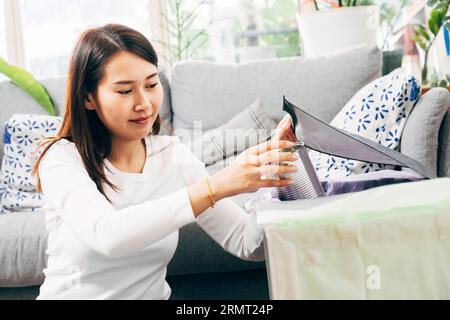 Les femmes asiatiques séparent les ordures à la maison. jeune femme triant et recyclant le plastique, le papier, la canette en aluminium et le récipient de nourriture aux poubelles dans le salon Banque D'Images